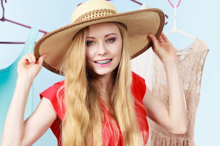 blond teenager on vacation wearing a sun hat and smiling with her braces